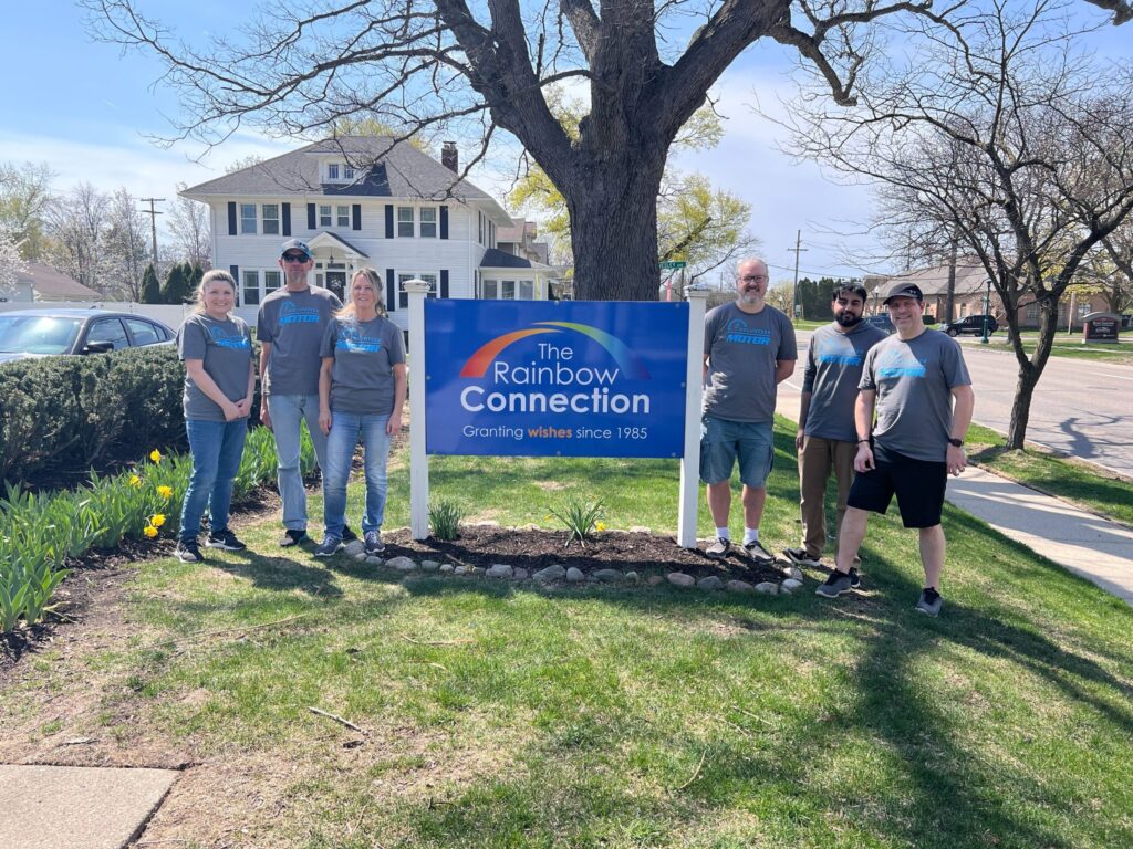 MOTOR volunteers standing by The Rainbow Connection sign in front of the organization’s office, supporting community service and charitable initiatives.