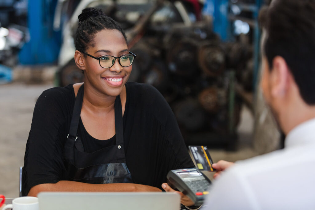 Female African American car auto parts owner Accepting credit card payments from customers in auto parts stores. business warehouse motor vehicle.